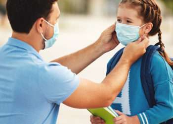 Un padre pone la mascarilla a su hija // iStock-evgenyatamanenko