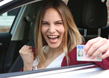 Una joven posando con un carnet de conducir // iStock/Joerg Siegert