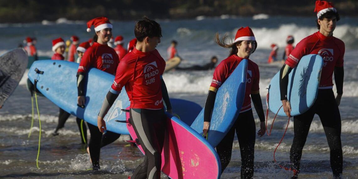 Decenas de personas disfrazadas de Papá Noel surfean durante la Papanoelada Surfera, en la playa de Patos. - Adrián Irago - Europa Press