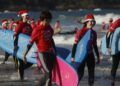 Decenas de personas disfrazadas de Papá Noel surfean durante la Papanoelada Surfera, en la playa de Patos. - Adrián Irago - Europa Press